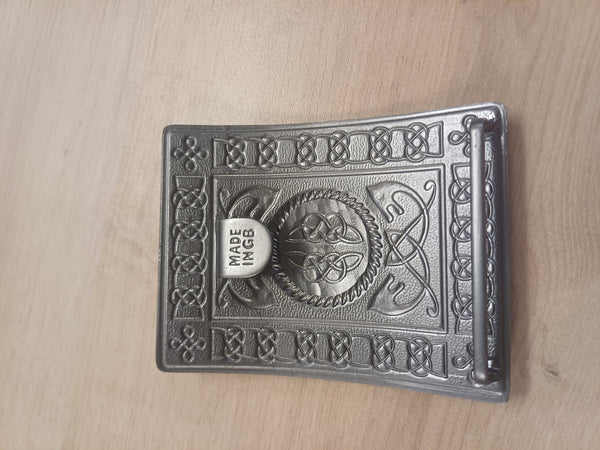 Decorative metal buckle with intricate designs on a wooden surface