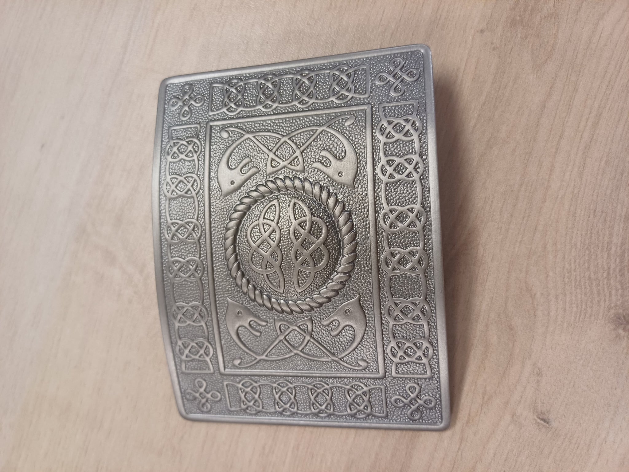 Decorative metal box with intricate Celtic knot patterns on a wooden surface