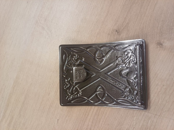 Decorative metal buckle with intricate designs on a wooden surface