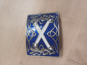 Decorative metal badge with a blue border and silver design on a wooden surface