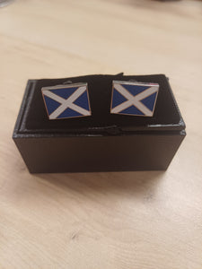 Pair of cufflinks with a blue and white design in a black box on a beige surface